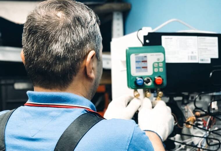 HVAC technician connecting service gauges to an air conditioning unit