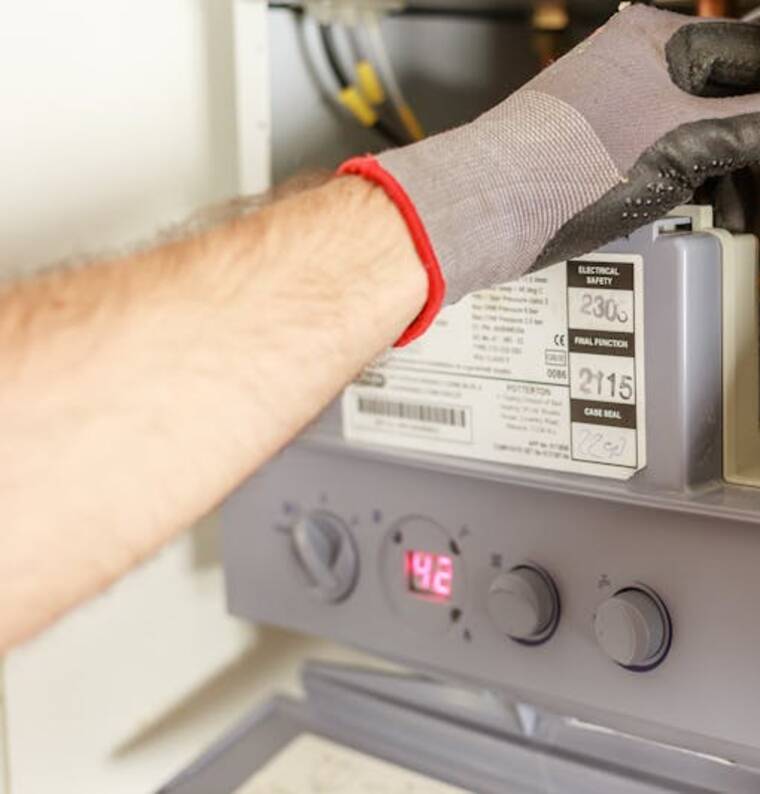 Gloved hand servicing a residential furnace control panel